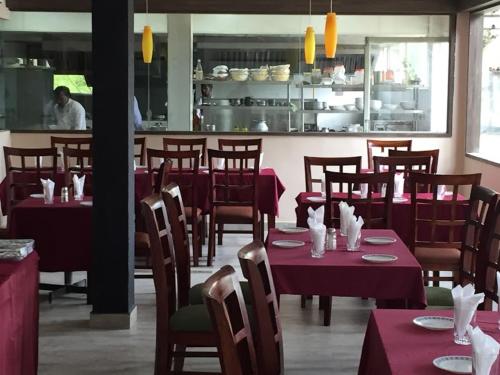 a restaurant with red tables and chairs and a chef in the kitchen at Pearlspot Hotel in Kumarakom