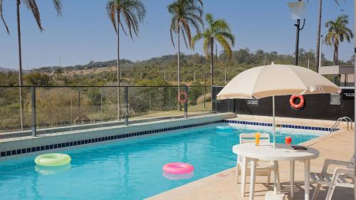 a swimming pool with a table and an umbrella at ibis Styles Taubate in Taubaté