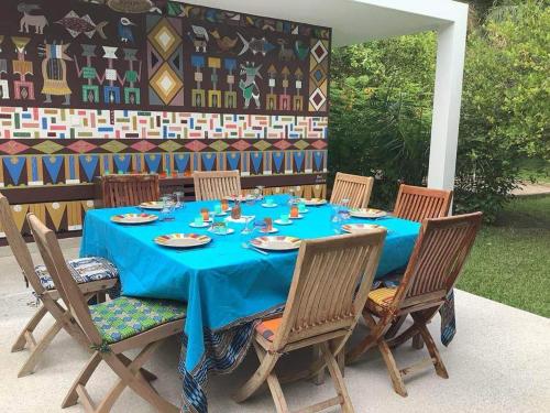 Villa CITRONS VERTS dans un parc arboré vue mer في كاب سكيرينج: طاولة مع كراسي وملابس الطاولة الزرقاء