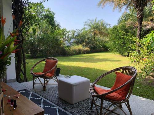 卡普斯基靈的住宿－Villa CITRONS VERTS dans un parc arboré vue mer，庭院里设有两把椅子和一张桌子