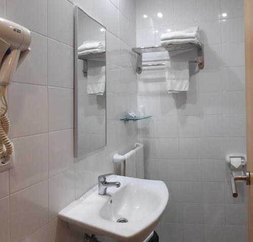 a white bathroom with a sink and a mirror at Hotel Varadoiro in Portonovo