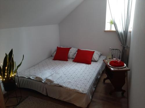 a bedroom with a bed with red pillows and a table at Agroturystyka Siedlisko 