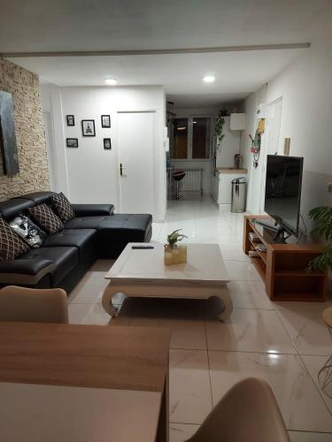 - un salon avec un canapé noir et une table basse dans l'établissement Apppartement Cosy 72m2, à Tarbes