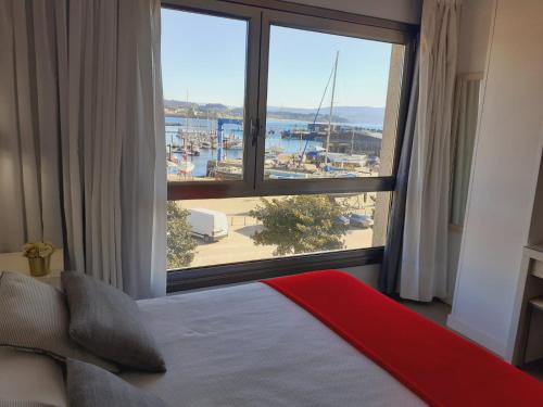 een slaapkamer met een groot raam met uitzicht op een jachthaven bij Hotel Varadoiro in Portonovo