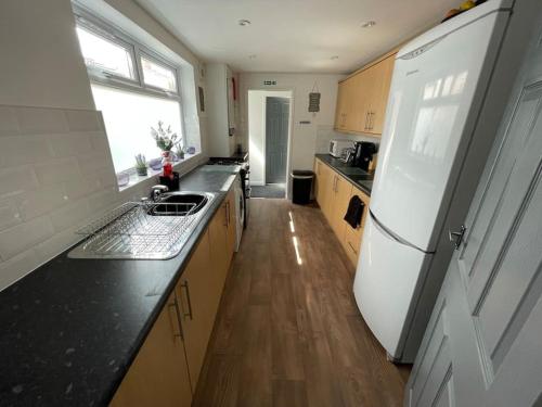a kitchen with a white refrigerator and a wooden floor at Lovely Seaside House in Cleethorpes Beachfront Area sleeps up-to 6 in Cleethorpes