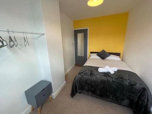 a bedroom with a bed and a yellow wall at Lovely Seaside House in Cleethorpes - sleeps 6 in Cleethorpes