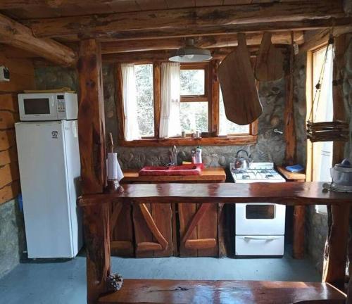 a kitchen with a table and a refrigerator in a cabin at Cabaña Mirador del Valle in Lago Puelo
