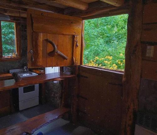 una cabaña con ventana y vistas al interior de una cocina en Cabaña Mirador del Valle en Lago Puelo