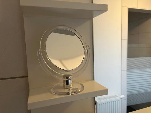 a round mirror on a shelf in a bathroom at Pension Blaue Nordseewelle in Neuharlingersiel