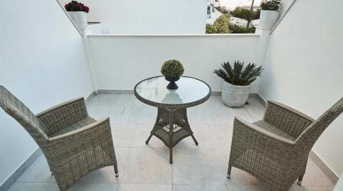a glass table with two chairs and a potted plant at Hostal Boutique Aurora in Nerja