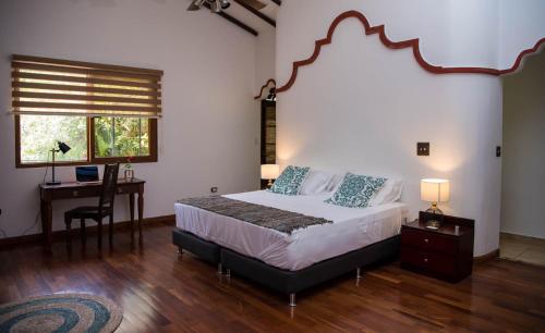 a bedroom with a bed and a desk and a window at Wanakaset Panama in Dolega