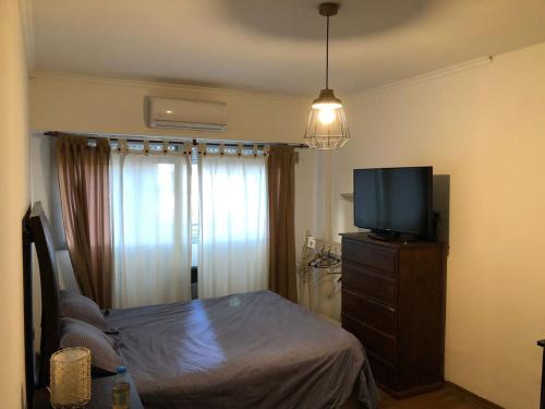 Dormitorio con cama y tocador con TV en Mono ambiente Oro 2700 en Buenos Aires