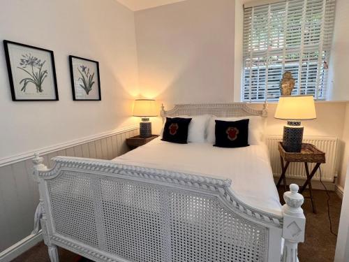 a bedroom with a white bed with two lamps at Rose Cottage at The Stables in Stannington