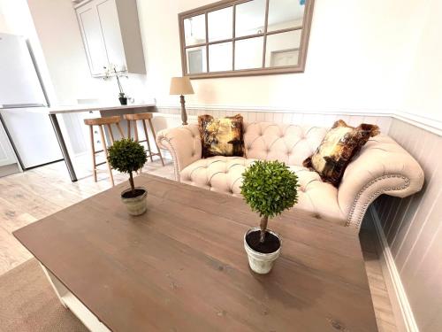 a living room with a couch and two potted plants at Rose Cottage at The Stables in Stannington