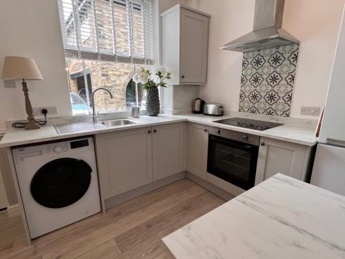 a kitchen with white cabinets and a sink and a dishwasher at Rose Cottage at The Stables in Stannington