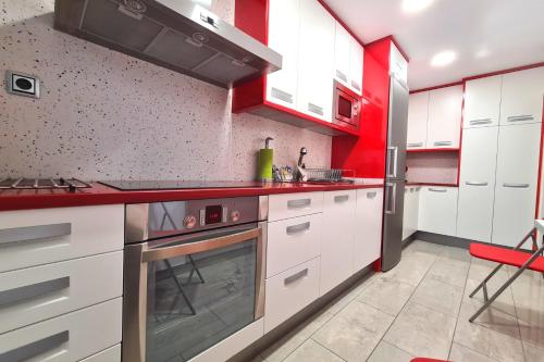 d'une cuisine avec des placards blancs et des touches de rouge. dans l'établissement Dos Torres Conde Aranda - Céntrico con estacionamiento Incluido, à Saragosse