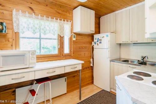 cocina con nevera blanca y ventana en Countryside riverside cabin for both winter and summer for max 15 persons en Janakkala