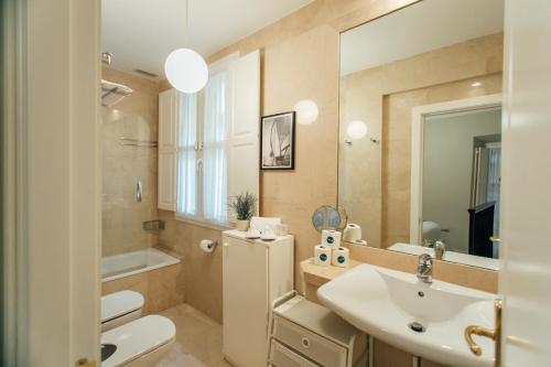 a bathroom with a sink and a toilet and a mirror at Comfortable duplex- 1Bd 2Bth- Dean Miranda in Seville