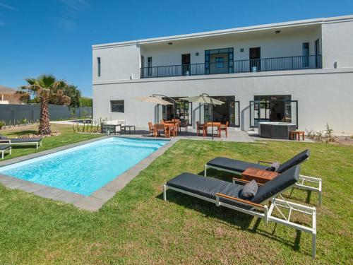 a villa with a swimming pool and a house at Glow Boutique Suites in Hermanus