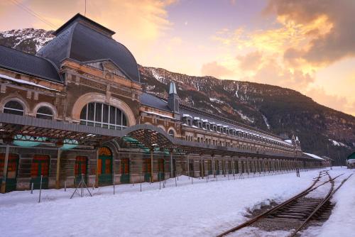 a train station covered in snow in front of a mountain at Apartamento La Campa in Canfranc-Estación