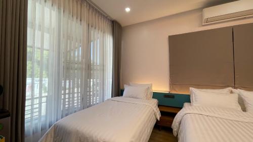 dwa łóżka w pokoju z oknem w obiekcie THA PAE SUNG - ท่าแพซุง w mieście Uthai Thani