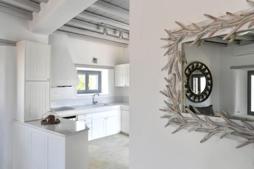 a kitchen with white cabinets and a mirror at SUNRAY Paros Beach front 2 bedroom house next to kite sports in Kampos Paros