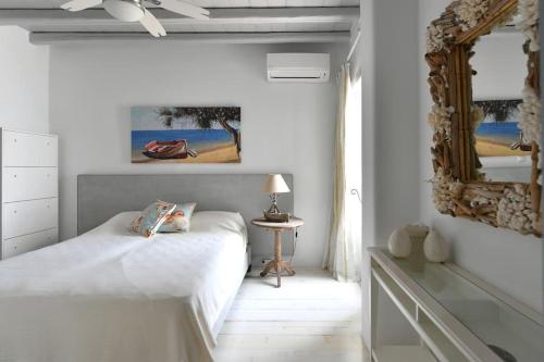 ein weißes Schlafzimmer mit einem Bett und einem Spiegel in der Unterkunft SUNRAY Paros Beach front 2 bedroom house next to kite sports in Kampos Paros