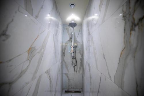 a bathroom with a shower with white marble walls at Adriatik Hotel, BW Premier Collection in Durrës