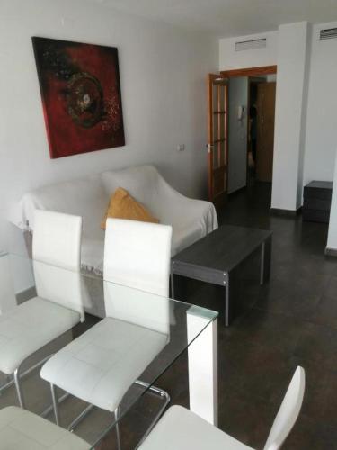 a living room with a glass table and white chairs at Apartamento Gloria Patricia in Alcantarilla
