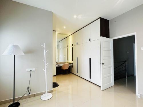 Cette chambre comprend des armoires blanches, une lampe et un bureau. dans l'établissement 《Untitled HomeStay》Sitiawan, à Sitiawan