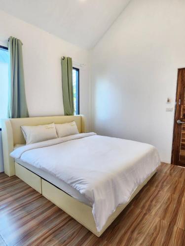 - une chambre avec un grand lit et des draps blancs dans l'établissement บ้านมีกิน ณ บึงโขงหลง, à Ban Don Klang