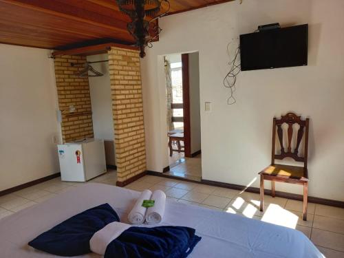 a room with a bed with a tv and a chair at Pousada Nova Conquista in Penedo