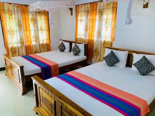 a bedroom with two beds with colorful sheets at Rich Resort & Restaurant in Anuradhapura
