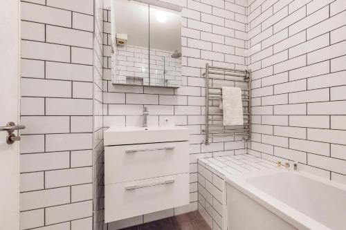 a white bathroom with a tub and a sink at Charming 1 bedroom flat with parking in Brentford in Brentford