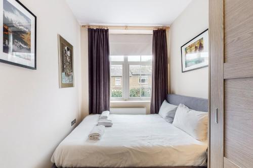Charming 1 bedroom flat with parking in Brentford في برينتفورد: غرفة نوم صغيرة بها سرير ونافذة
