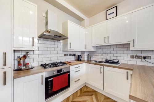 een witte keuken met witte kasten en houten vloeren bij Charming 1 bedroom flat with parking in Brentford in Brentford