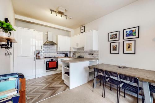 een keuken met witte kasten en een houten tafel bij Charming 1 bedroom flat with parking in Brentford in Brentford