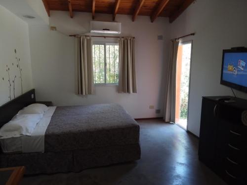 1 dormitorio con 1 cama, TV y ventana en Complejo El Peregrino en Cortaderas