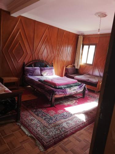 a bedroom with a bed and a wooden wall at Gite Oukaimeden in Oukkainrdem