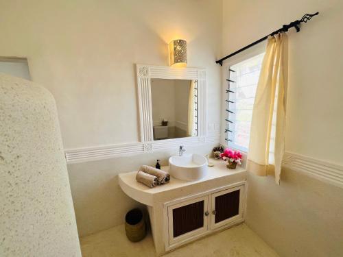 uma casa de banho branca com um lavatório e um espelho em Beba.Beach.House em Watamu