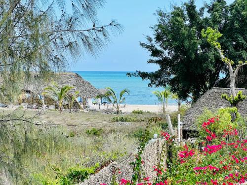 a view of the beach from a garden with flowers at Beba.Beach.House in Watamu
