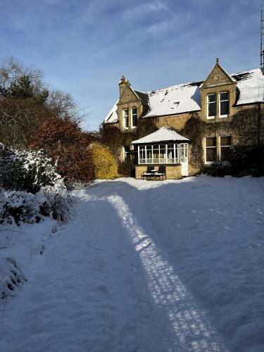 a snow covered driveway leading to a large house at St Duthus Villa Guesthouse in Tain