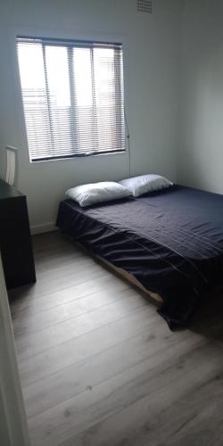 Simple room في Riverwood: سرير في غرفة مع نافذة كبيرة