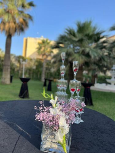 a table with wine glasses and a vase of flowers at Adriatik Hotel, BW Premier Collection in Durrës