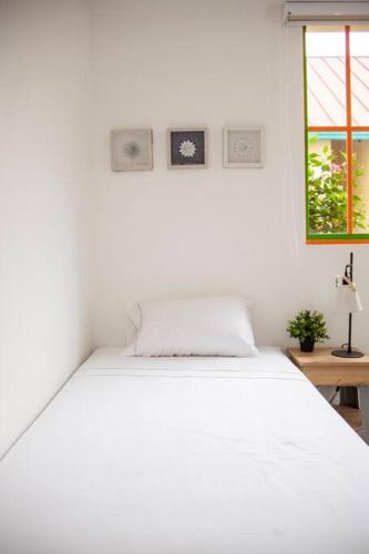 a white bed in a white room with a window at Duplex Familiar Apartment Nature in Guatapé