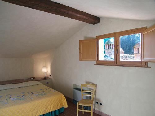 a bedroom with a bed and a window and a chair at Appartamento Geranio in San Miniato