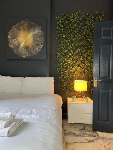 a bedroom with a bed and a lamp and a painting at Duke and Duchess Apartments and Rooms - Private in Room Hot Tub Suites in London