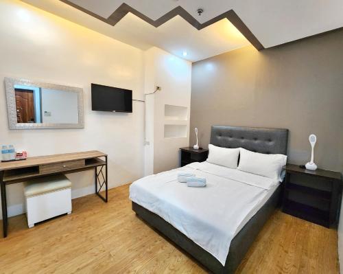 Dormitorio con cama, escritorio y TV en New Kong's Hotel en Olongapo