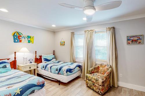 1 dormitorio con 2 camas, silla y ventana en Gem of Venado, en Panama City Beach