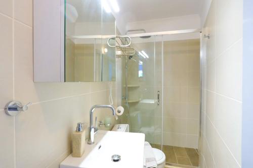 y baño con lavabo y ducha con espejo. en Alexandra Apartment, en Nisakion